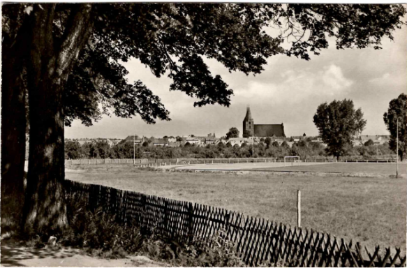 Landschaft mit einer Kirche im Hintergrund und einem Zaun im Vordergrund.