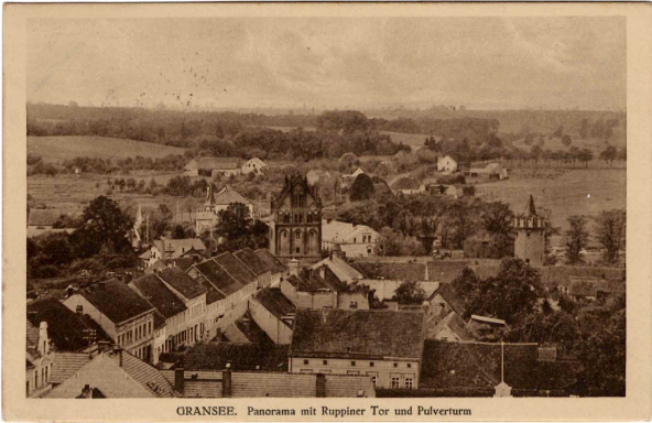 Blick auf eine ländliche Stadt mit Häusern und Feldern im Hintergrund.