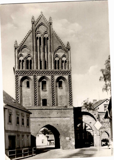 Historisches Gebäude mit markantem gotischen Turm und umgebenden Häusern.