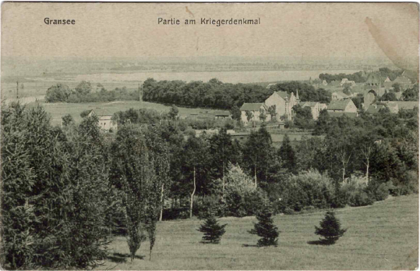 Blick auf eine Landschaft mit Bäumen und einem kleinen Dorf im Hintergrund.