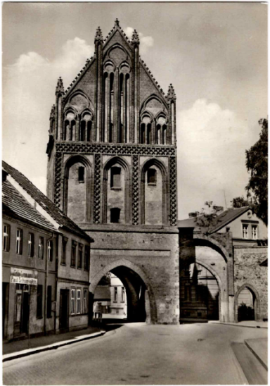 Historisches Stadttor mit gotischer Architektur in einer ruhigen Straßenszene.