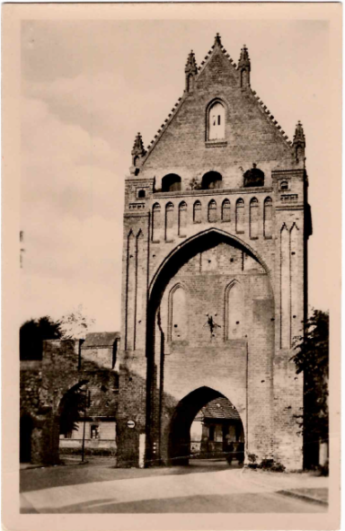 Historische Toranlage mit gotischer Architektur und einem klaren Himmel im Hintergrund.