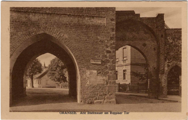 Historisches Tor mit zwei Bögen und Sicht auf Gebäude im Hintergrund.