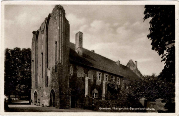 Historisches Gebäude mit großem Mauerwerk und begrünten Anlagen drumherum.